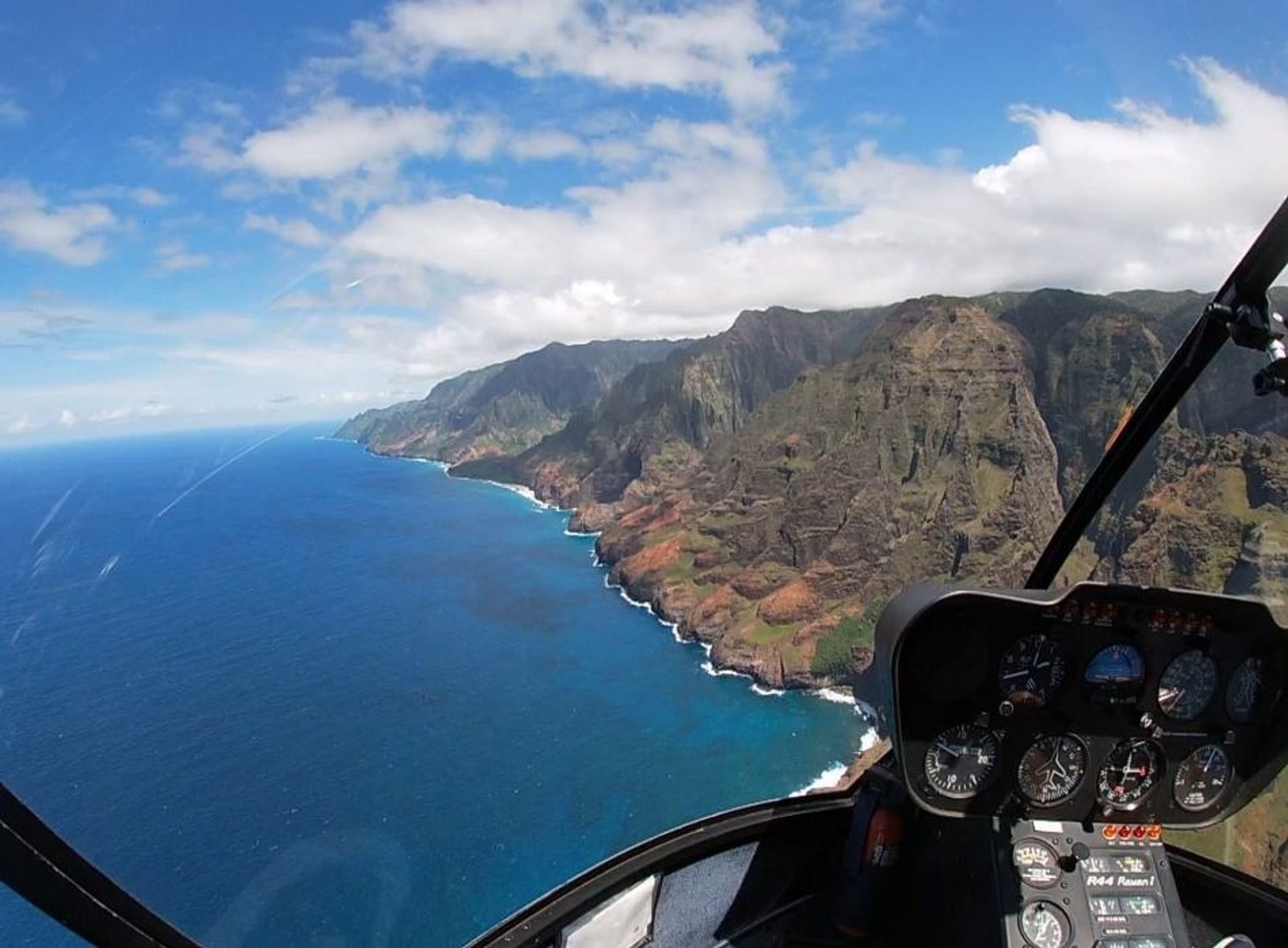 Cockpit view along the Nā Pali Coast with the instrument panel in the foreground and cliffs stretching to the horizon
