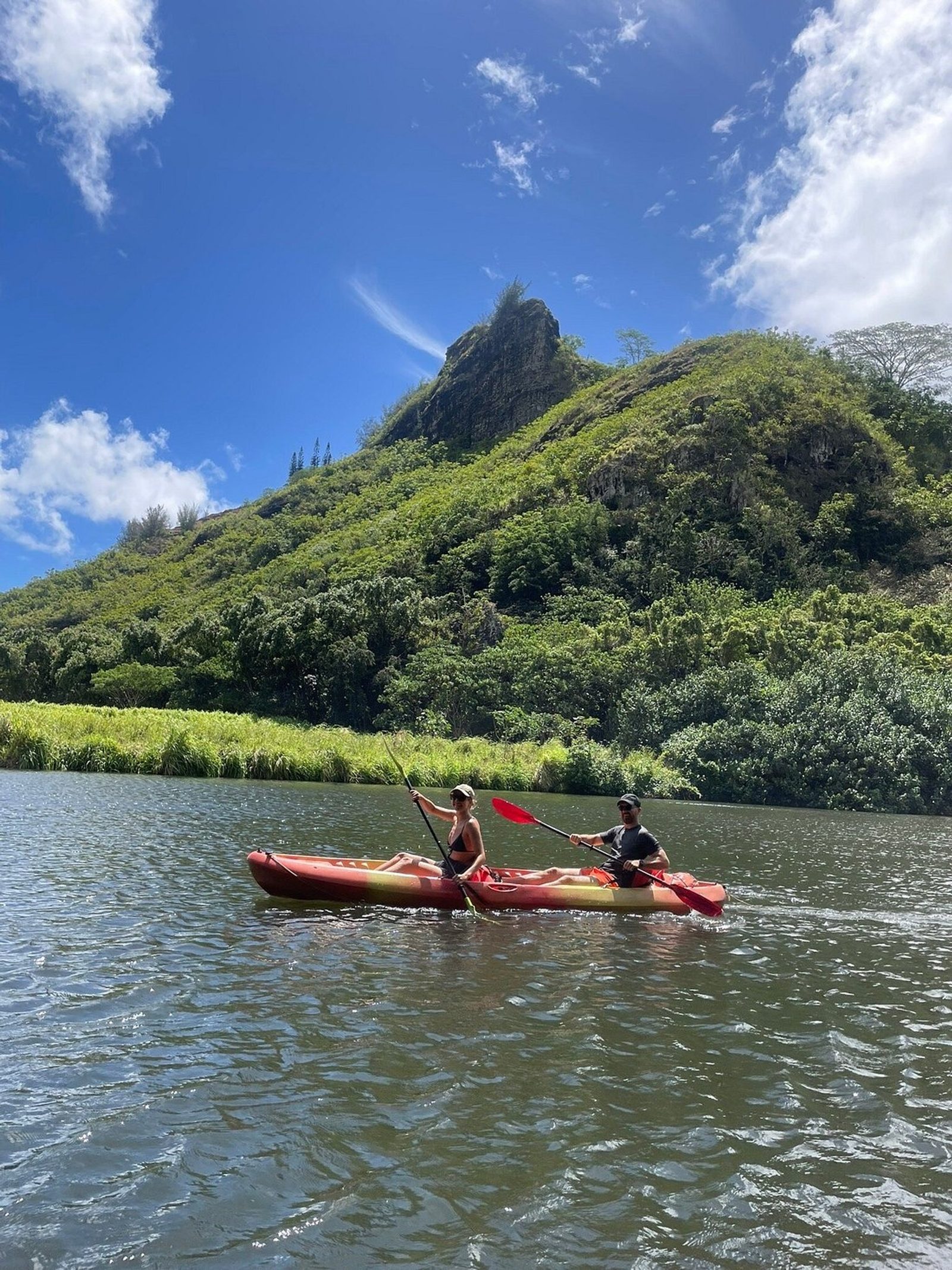 A kayaker on the river with the Sleeping Giant ridge rising green behind