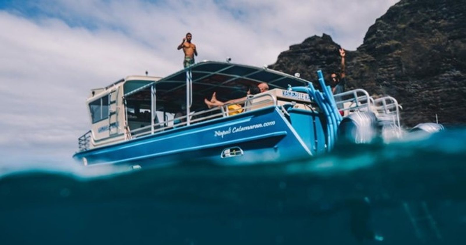 A guest diving off the catamaran's swim platform, photographed from water level